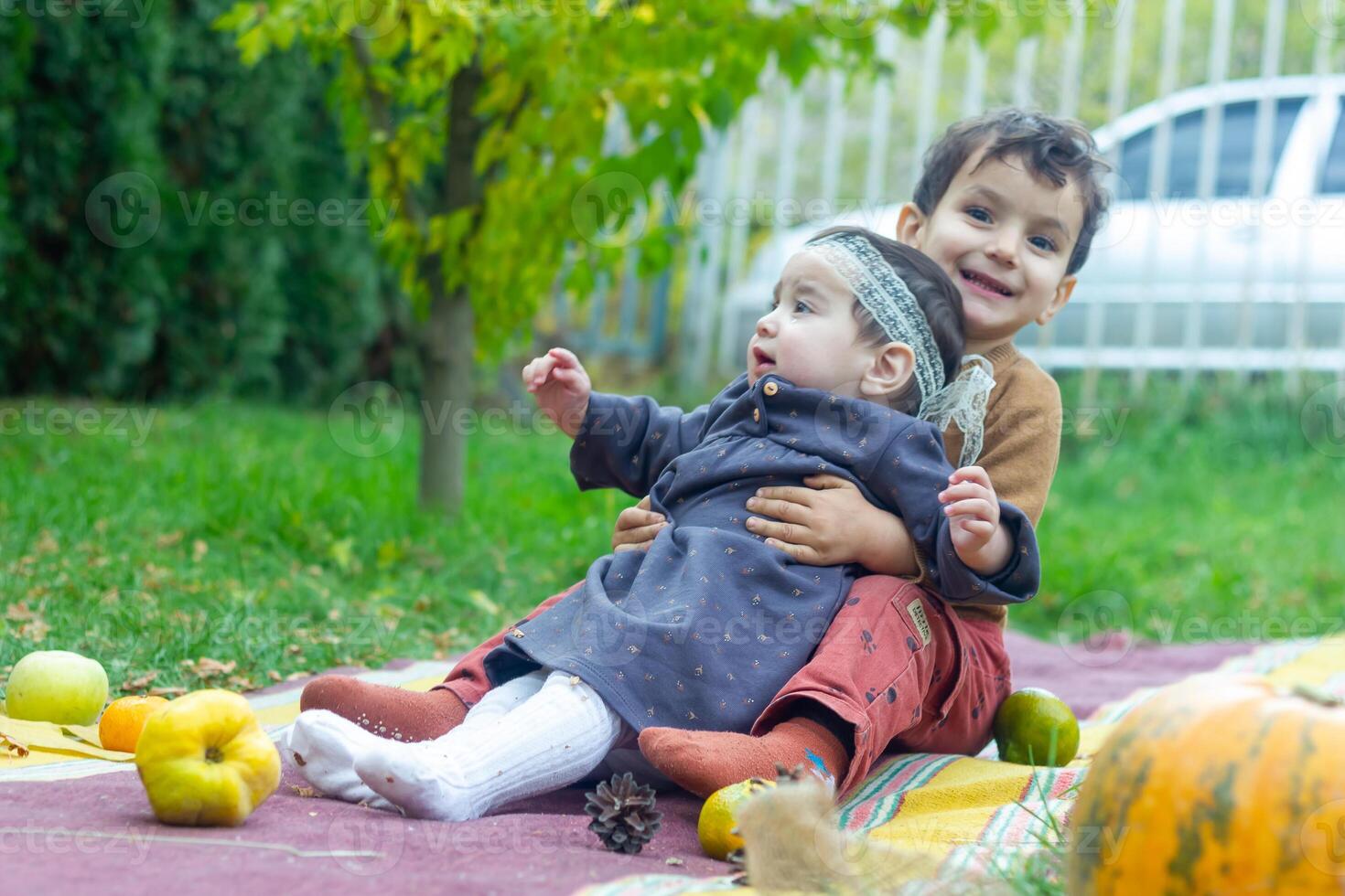 the little children are playing in the park with fruits, little girl and boy in the autumn park photo