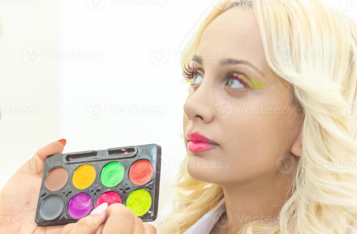 pretty young woman applying make up in beauty salon photo