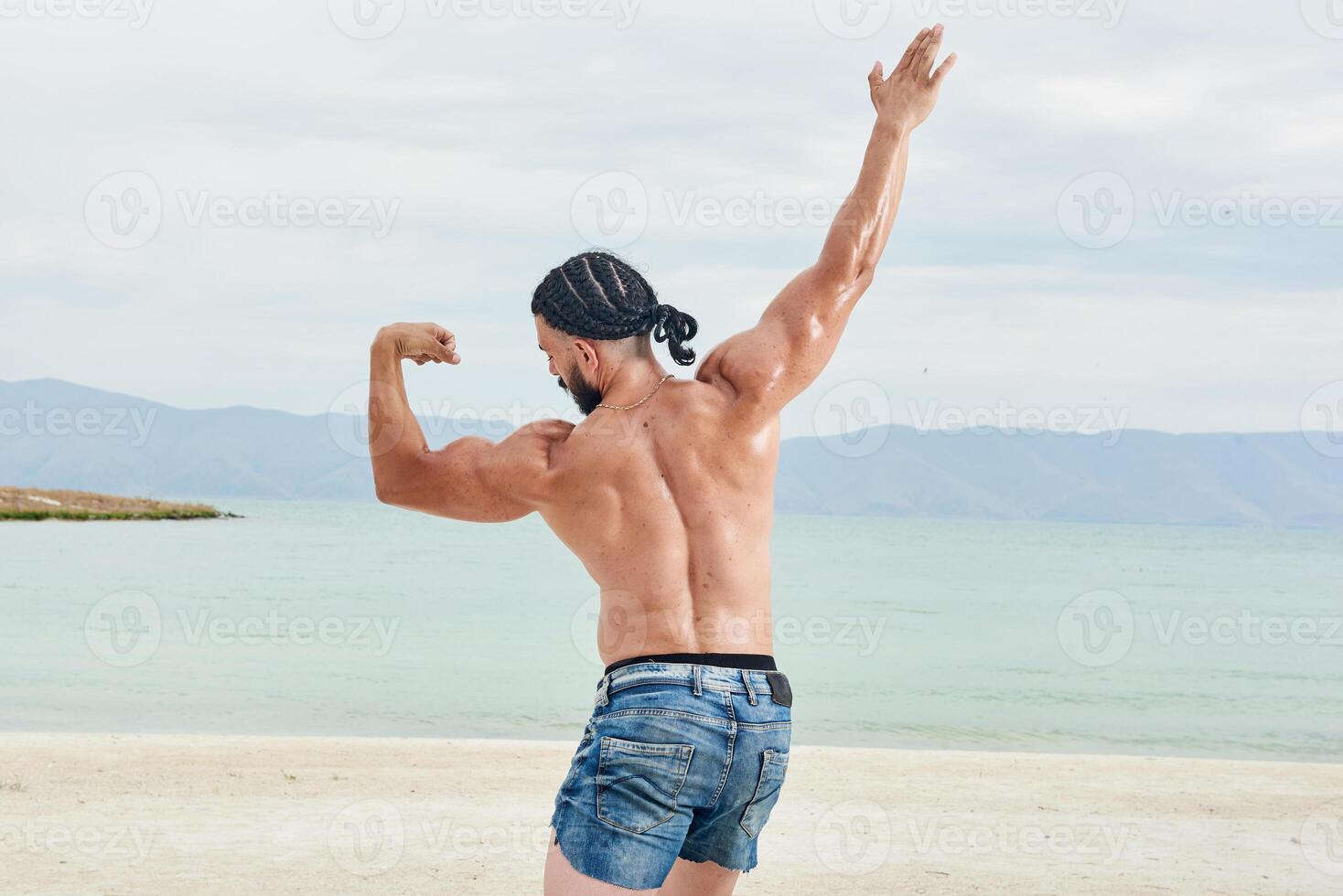 young muscular man exercising on the beach, young muscular man doing bodibuilding exercises on the beach, athletic young man on the beach photo