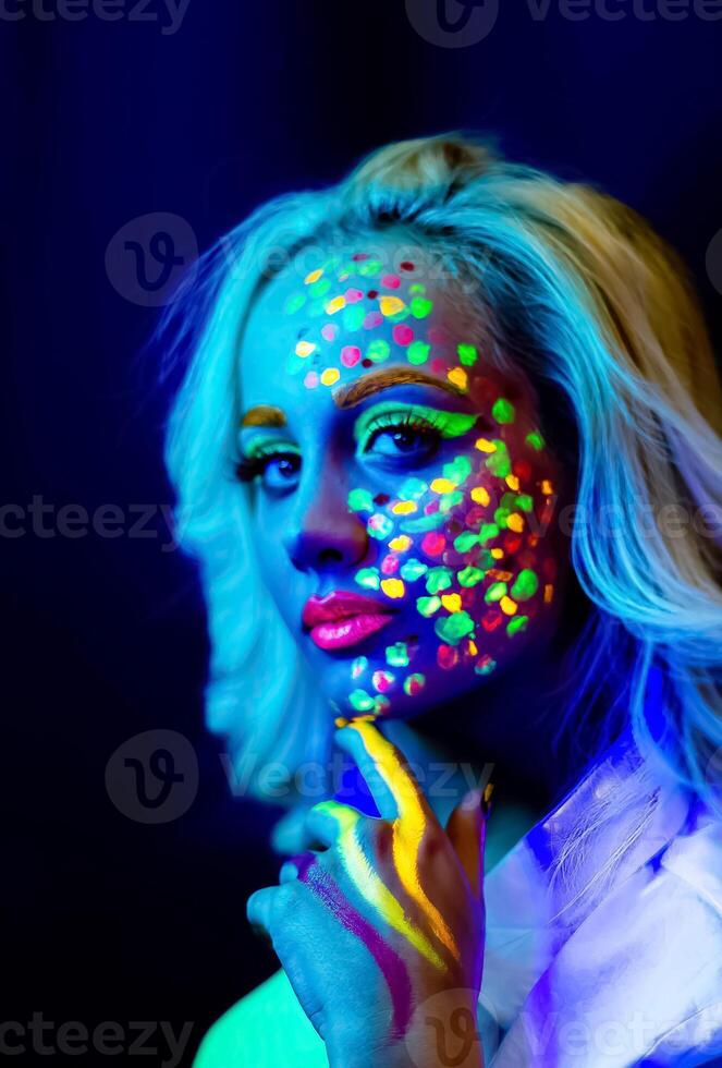 retrato de un mujer con pintado rostro, mujer con uv maquillaje en estudio, retrato de un mujer en carnaval mascarilla, el mujer es decorado en un ultravioleta polvo foto