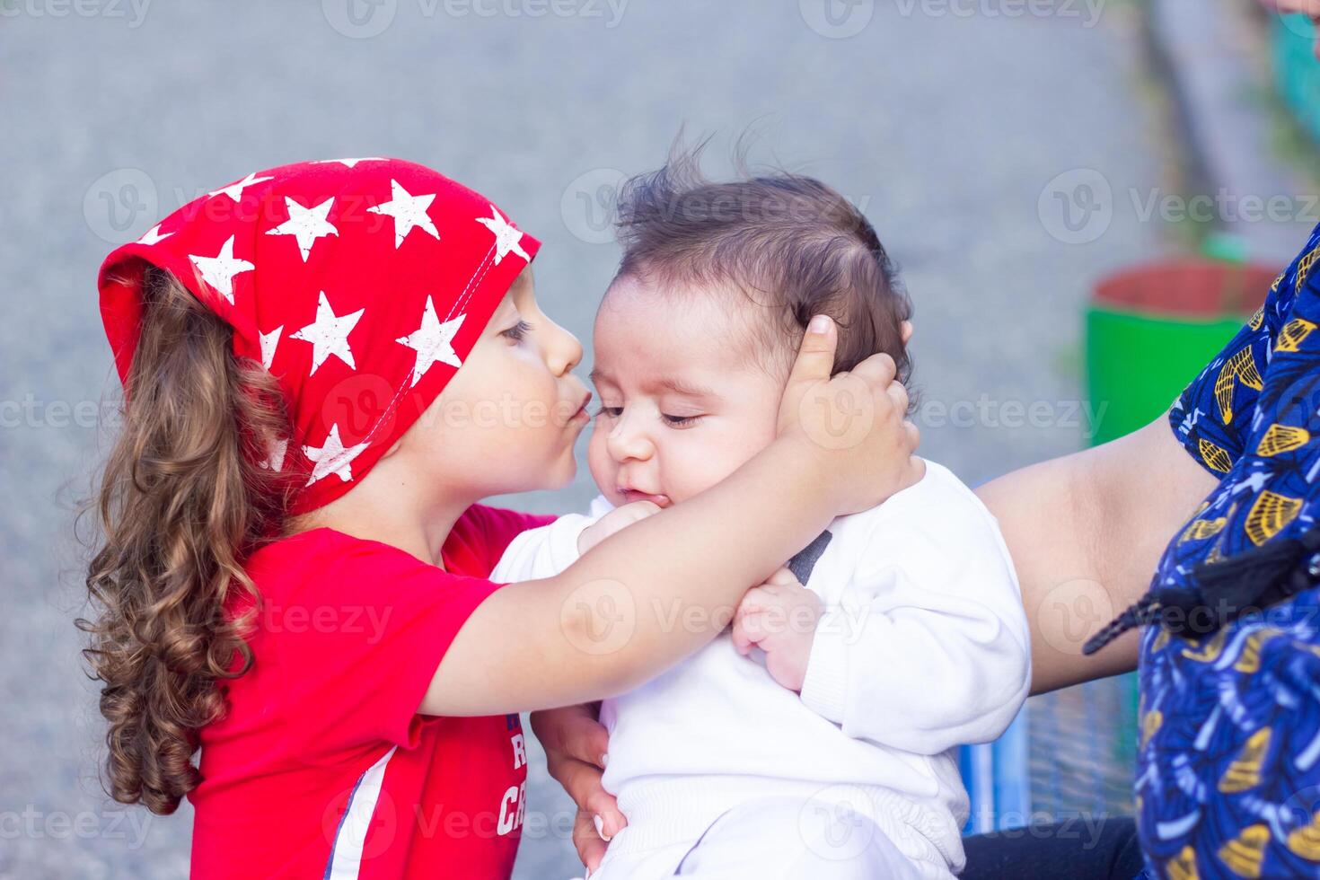 el pequeño chico en el parque es besos su recién nacido hermano foto