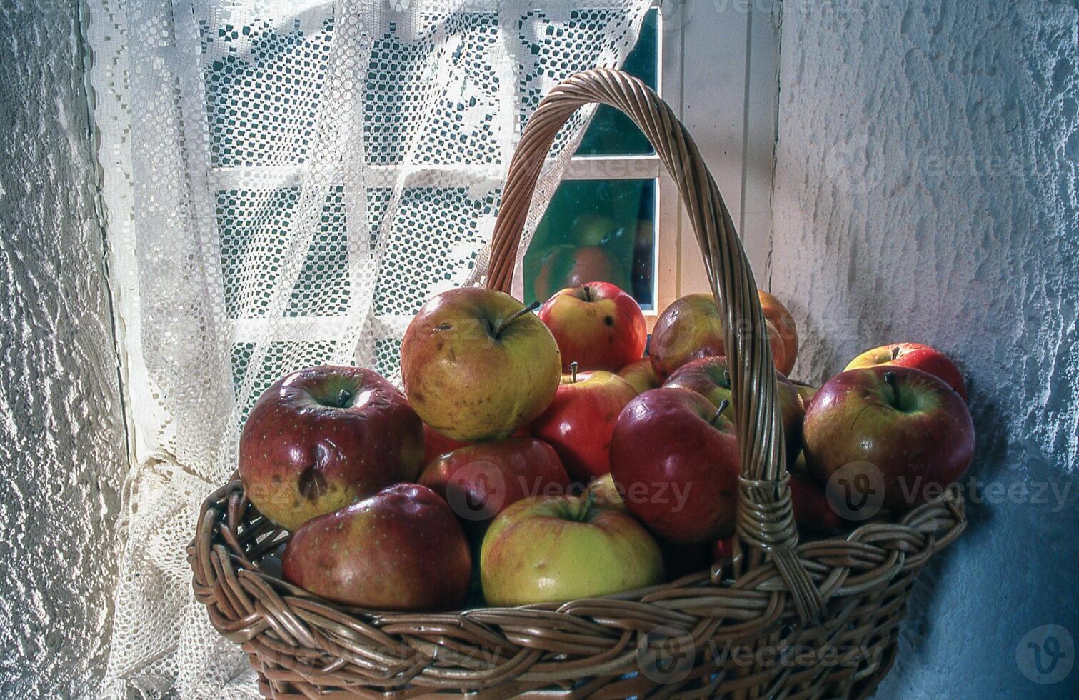 a basket filled with apples sitting on a window sill photo