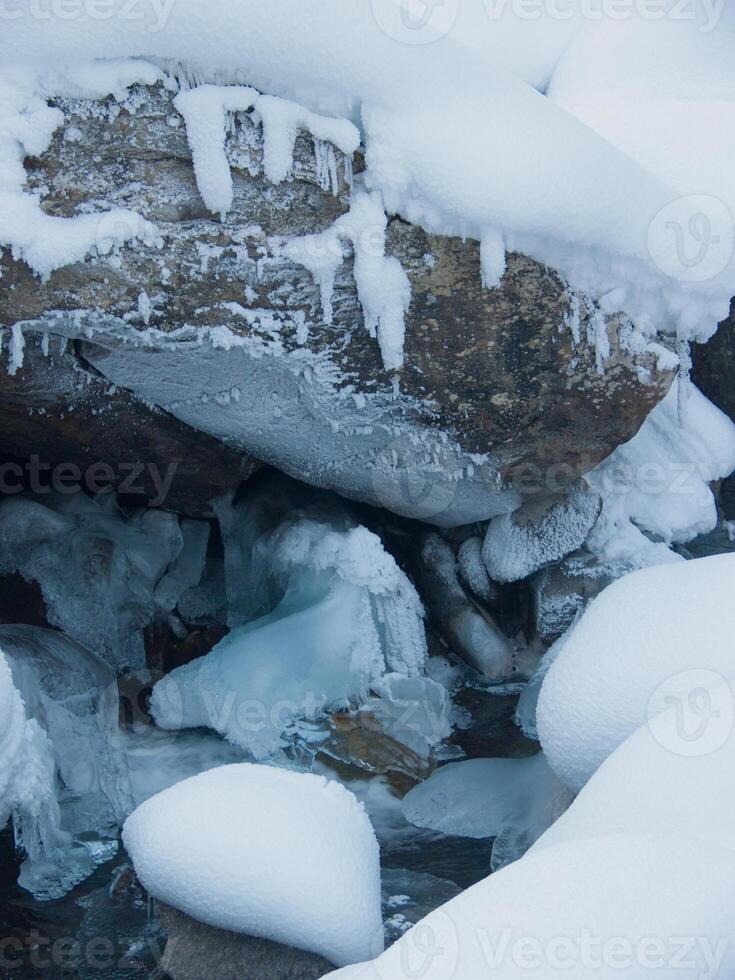 a rock with ice on it and a stream photo