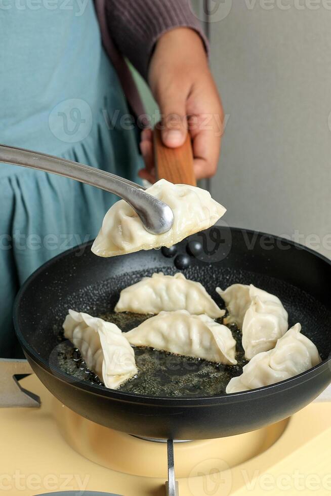 Cooking Gyoza Japanese Potsticker Dumpling on Black Pan, photo