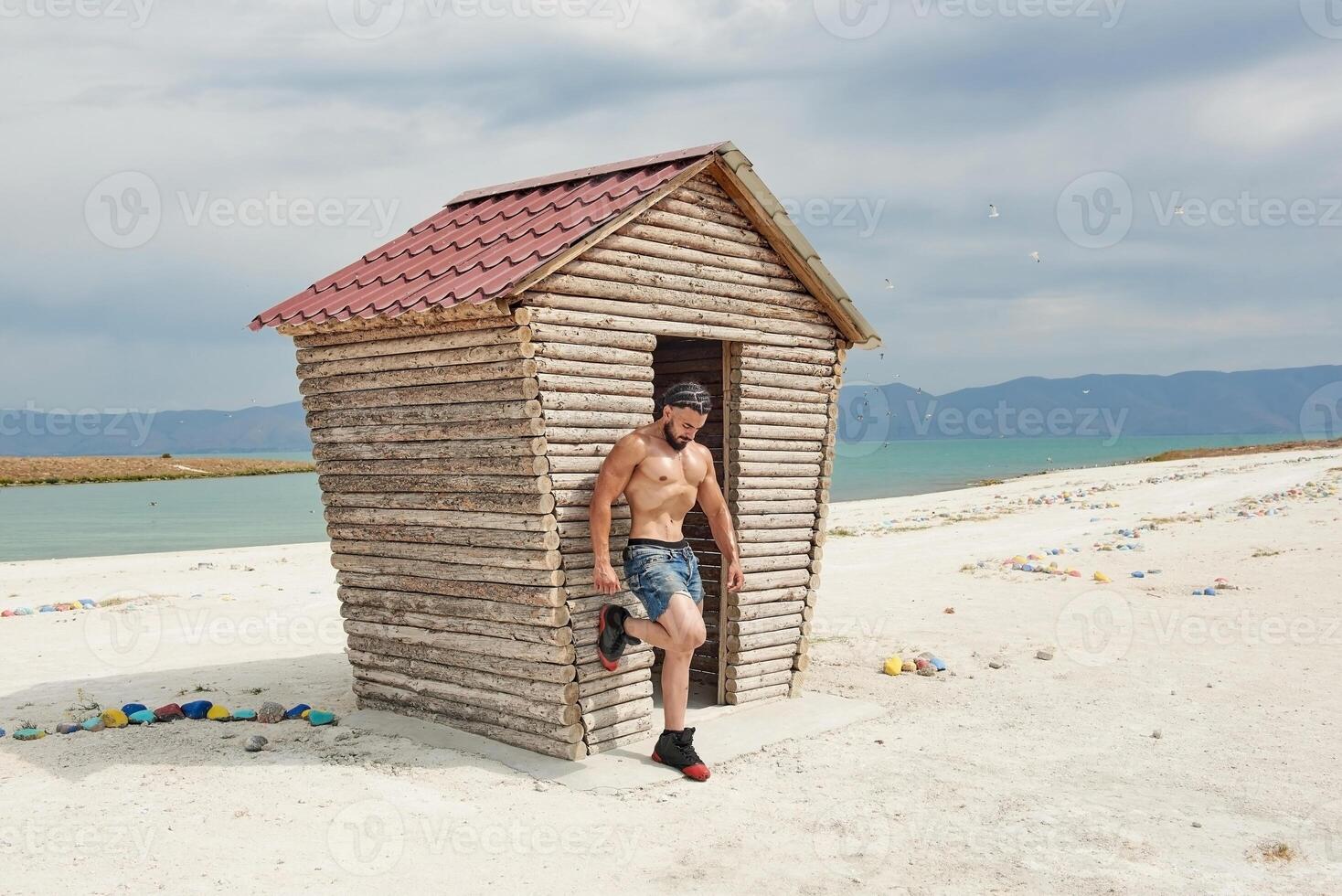 young muscular man exercising on the beach, young muscular man doing bodibuilding exercises on the beach, athletic young man on the beach photo