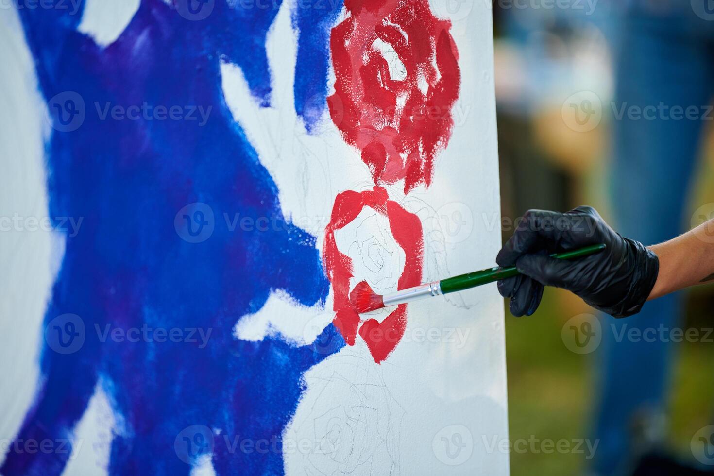 Artist hand in black gloves holds paint brush and draws abstract surreal image on white canvas photo