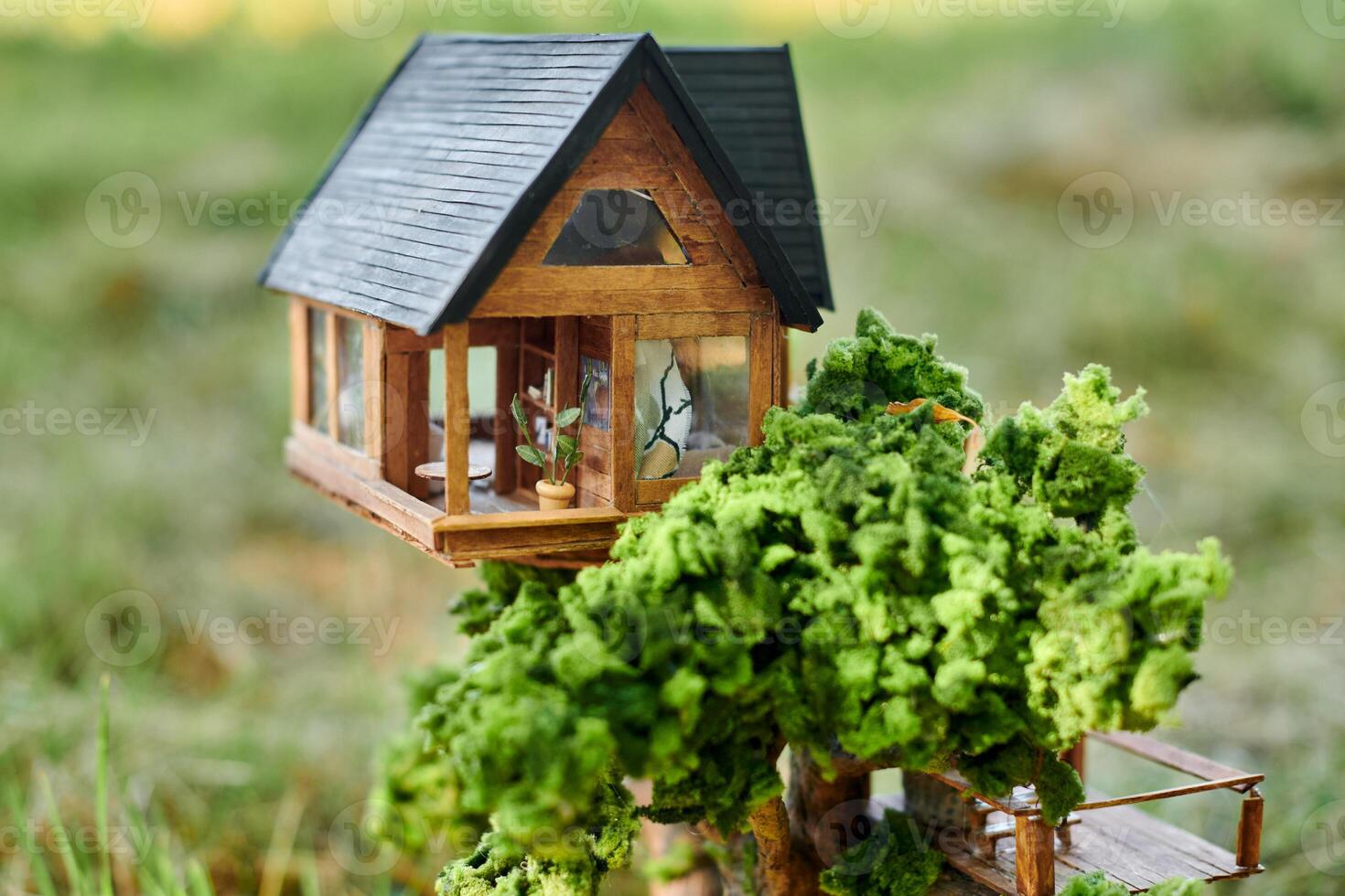 Little dollhouse on front lawn, cute small decorative house on green grass field, copy space photo