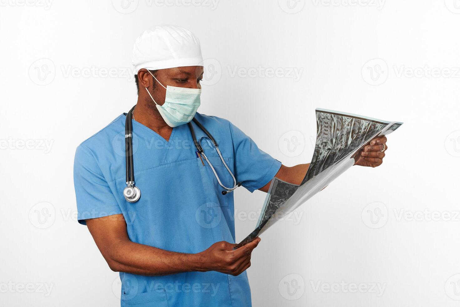 Black surgeon doctor man in blue coat white cap and surgeon mask holds x ray image, white background photo