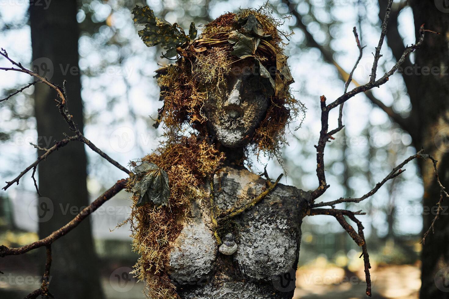 Creepy witch statue art object on forest background made of mud plaster and dry grass gloomy statue photo