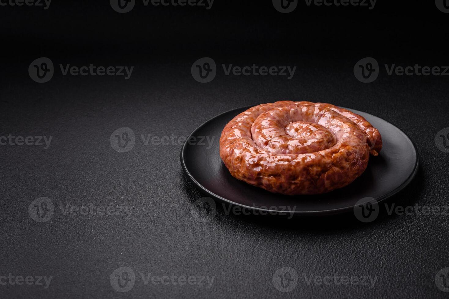 Delicious grilled sausage in the form of a ring with salt, spices and herbs photo