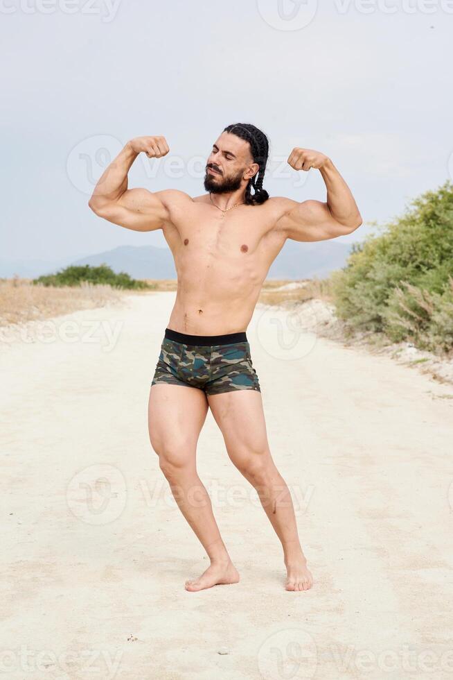 joven muscular hombre hacer ejercicio en el playa, joven muscular hombre haciendo culturismo ejercicios en el playa, atlético joven hombre en el playa foto