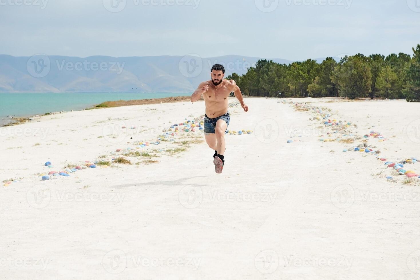 young muscular man exercising on the beach, young muscular man doing bodibuilding exercises on the beach, athletic young man on the beach photo