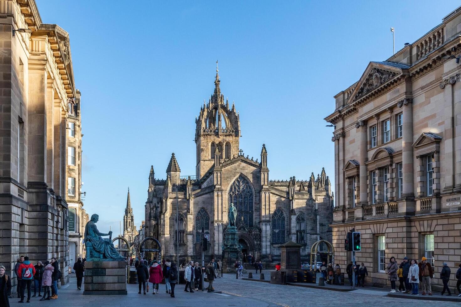 Sunny day view of a bustling city street with historic architecture and pedestrians in Edinburgh, Scotland. photo