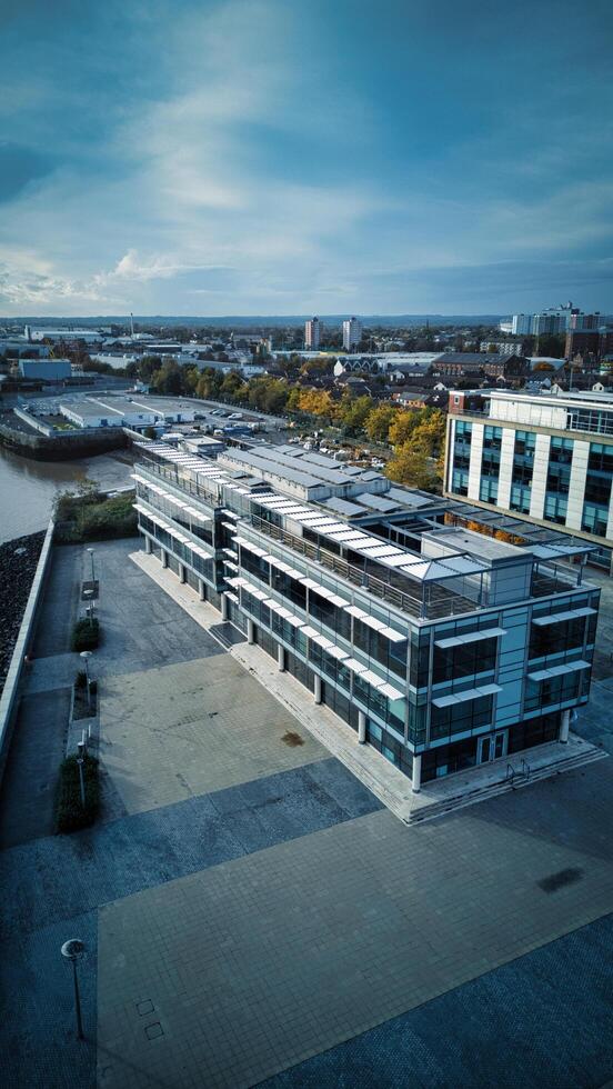 Modern office building with a rooftop terrace, overlooking a river and cityscape under a cloudy sky in Hull, England. photo