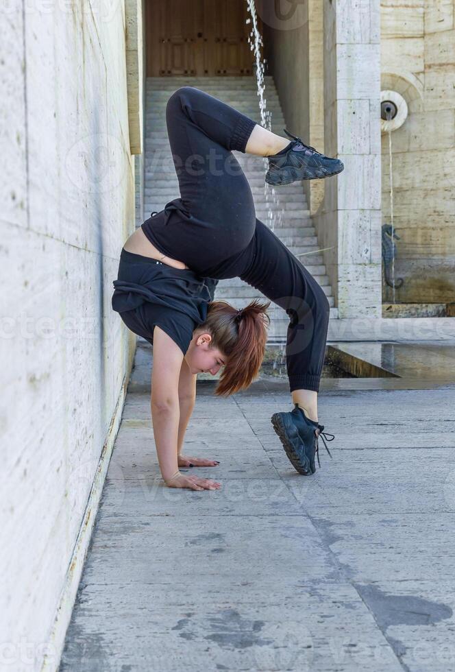 joven niña haciendo ejercicio en el ciudad, mujer haciendo yoga ejercicio, persona haciendo extensión, mujer relajante en el ciudad, bonito niña haciendo aptitud ejercicio foto