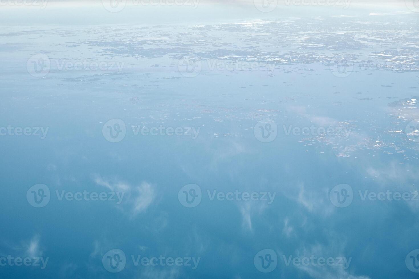 Aerial view from airplane window over clouds top to cold north sea, winter fresh frosty air photo