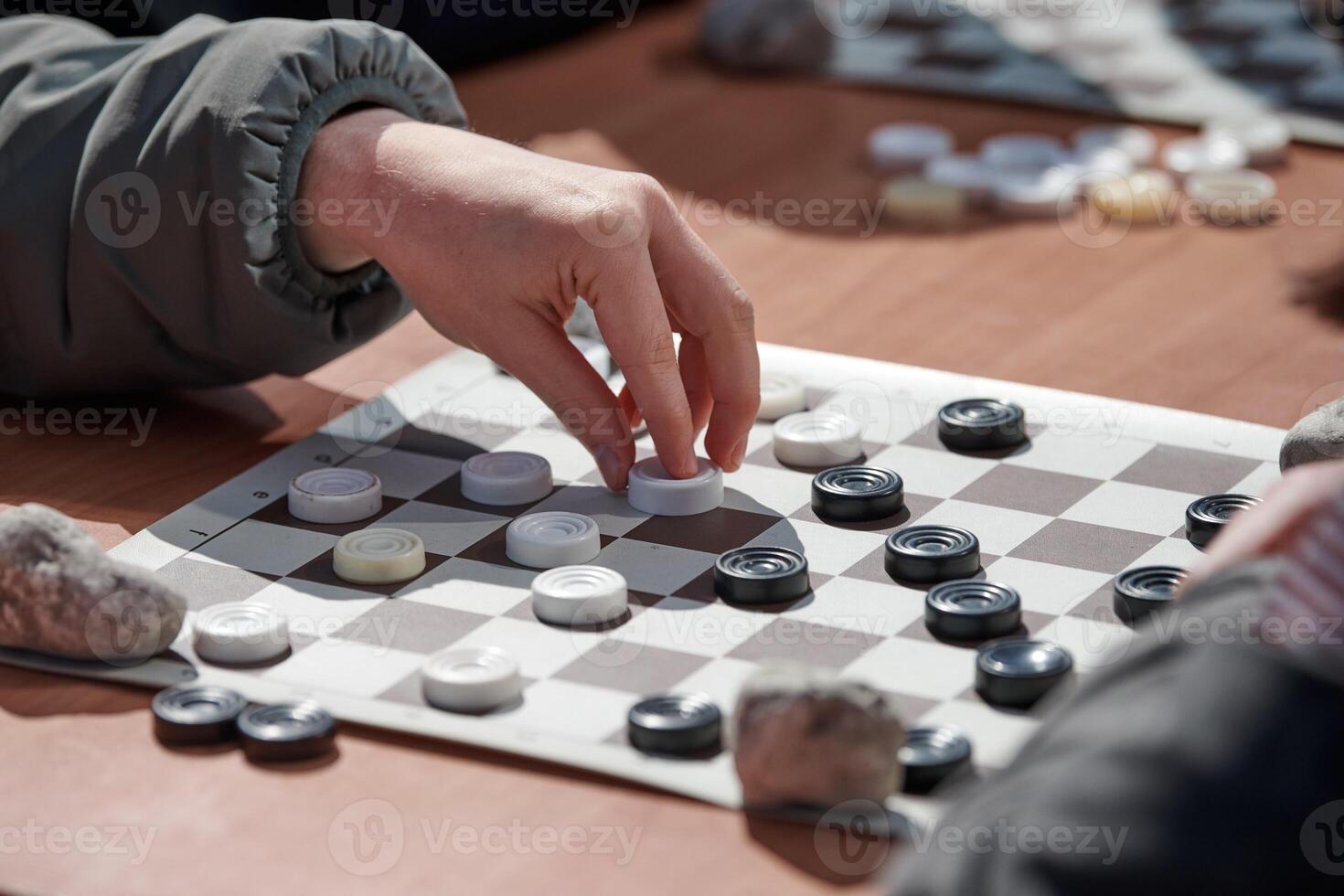 Outdoor checkers tournament on paper checkerboard on table, close up players hands photo