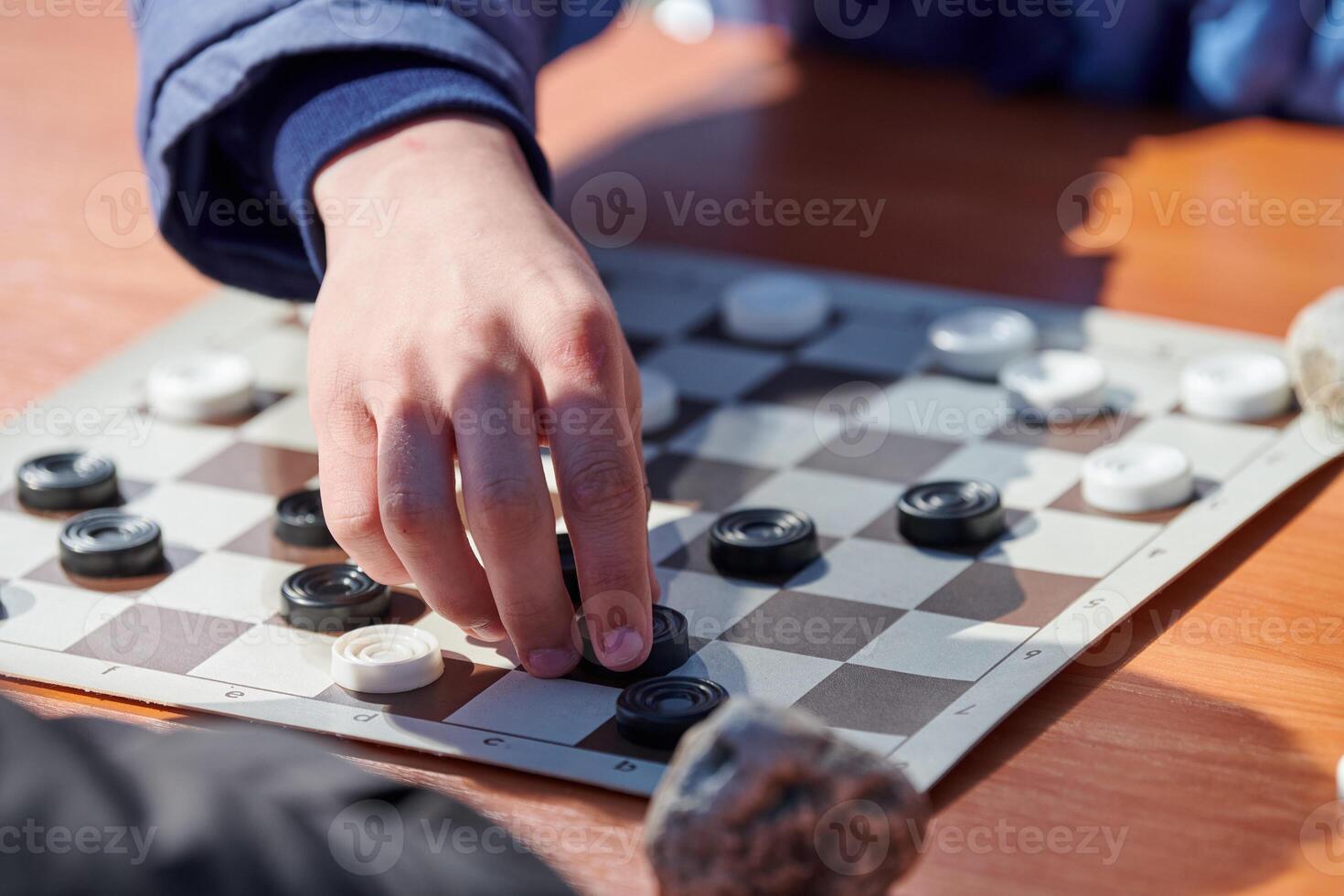 Outdoor draughts competition on paper checkerboard on table, close up players hands photo