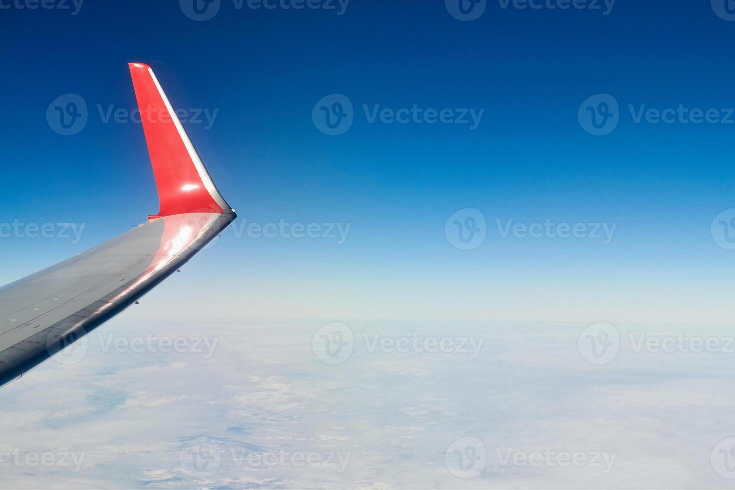 Airplane wing over clouds aerial top view from aircraft window, thick white blue clouds photo