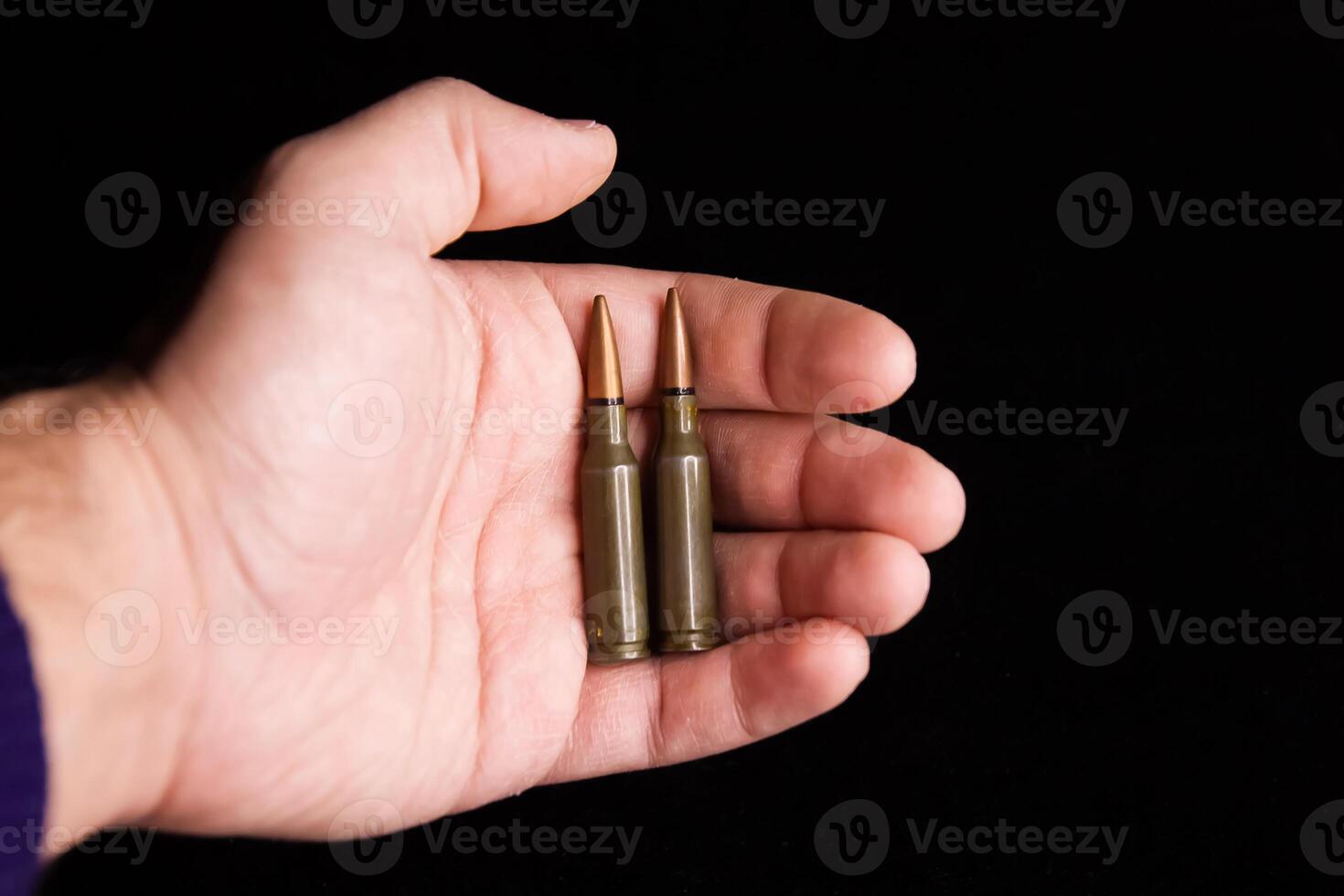 bullets in a hand, hand holding a bullet on black background photo