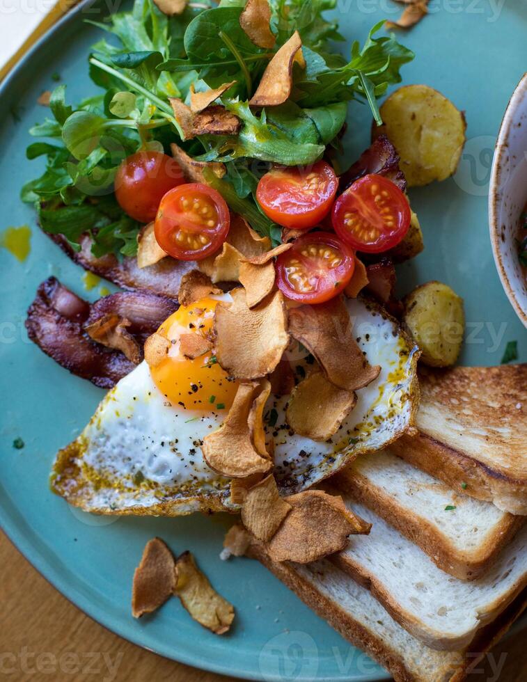 Breakfast with fried eggs, bacon, toasts and vegetable salad photo