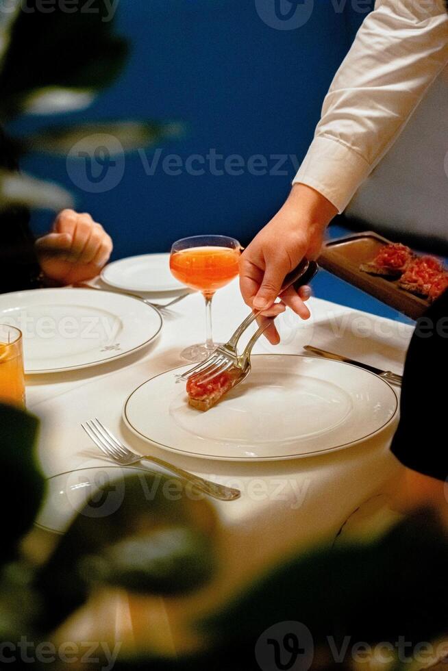 Closeup of female hand pouring orange juice into glass in restaurant. photo