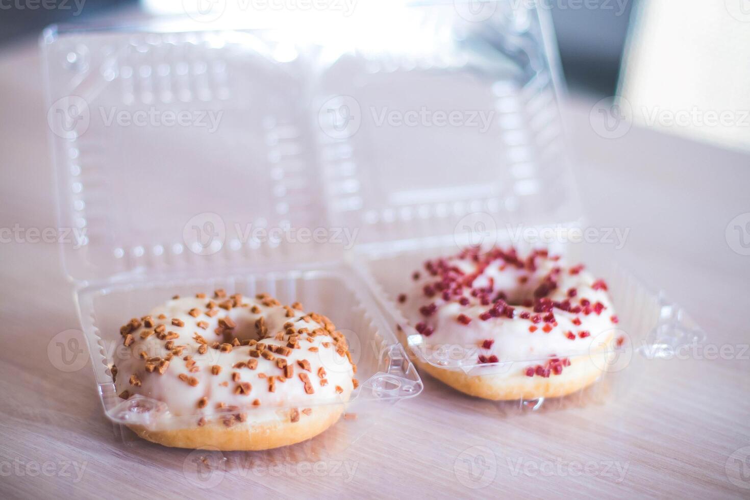Donuts in a plastic box on a wooden table. Selective focus. photo