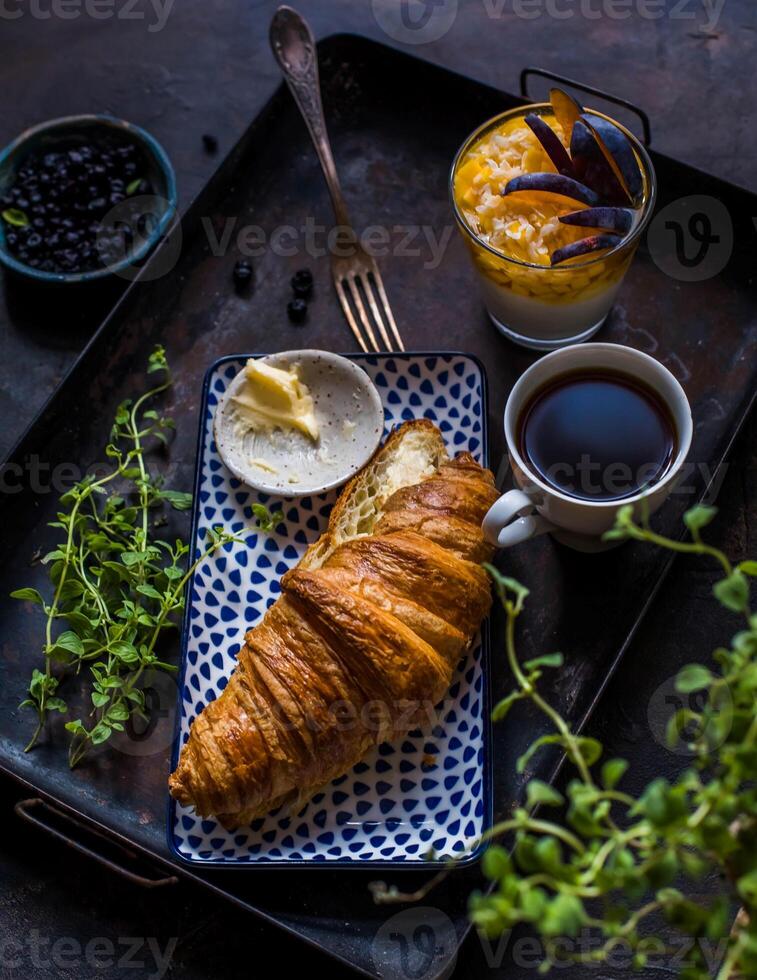 Breakfast with coffee and croissant on dark rustic background photo