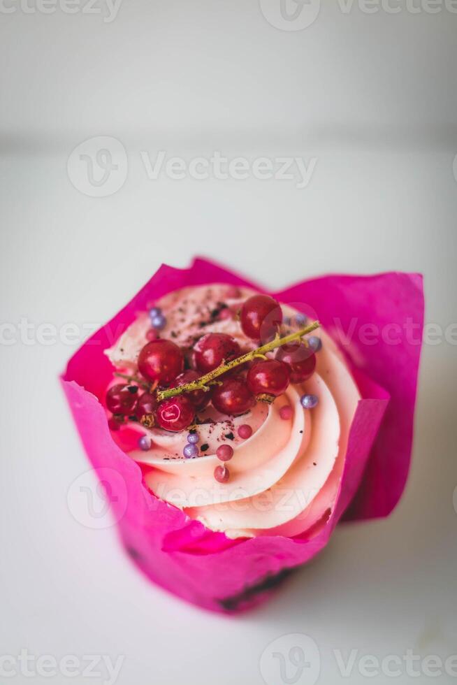 cupcake with red currant and pink cream on a white background photo