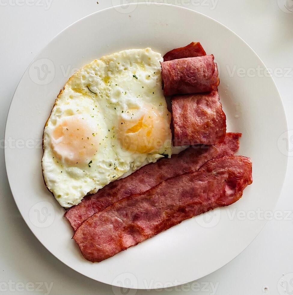 Breakfast with fried eggs, bacon and sausage on white background. photo