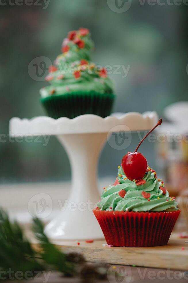 Christmas cupcakes with green cream frosting and red cherry on top photo