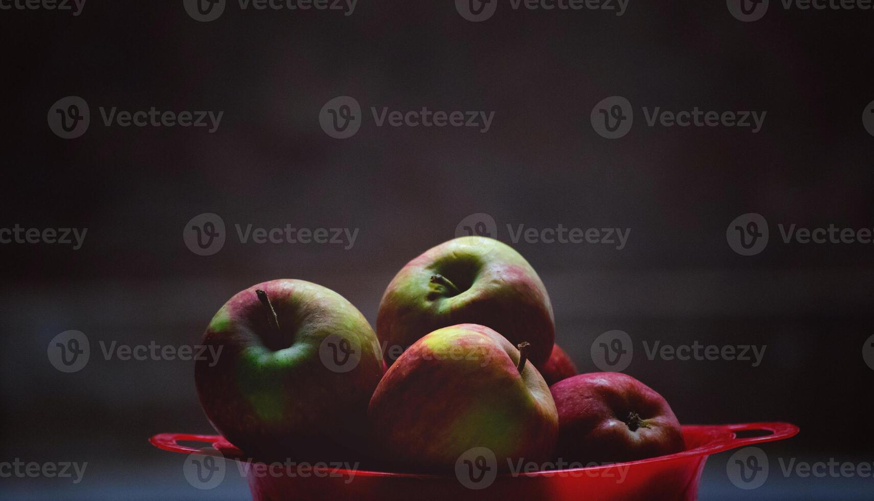 Red apples in a red bowl on a dark background. Selective focus. photo