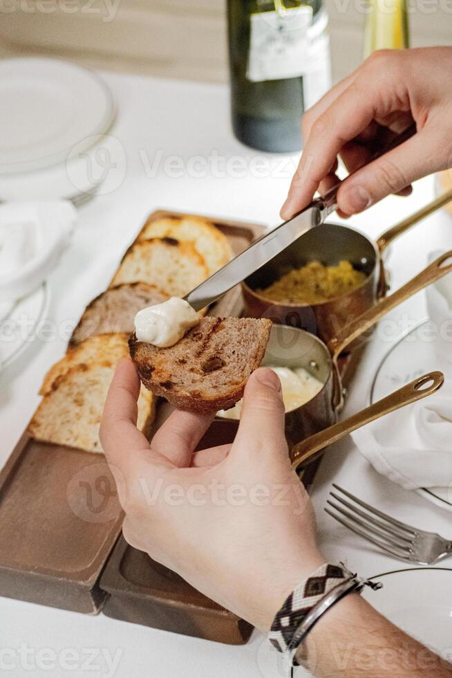 cropped image of woman cutting toast with butter and knife at table photo