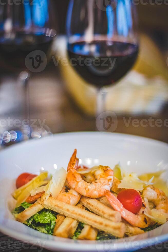 salad with shrimps in white plate and red wine glass photo