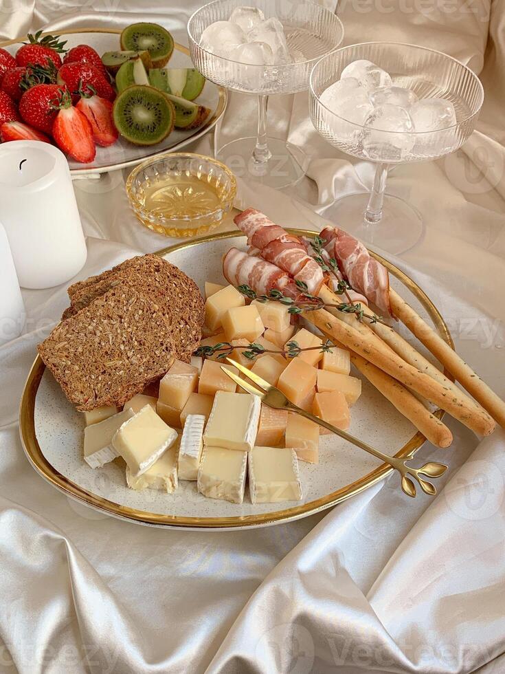 Cheese platter with fruits and bread on a white tablecloth photo