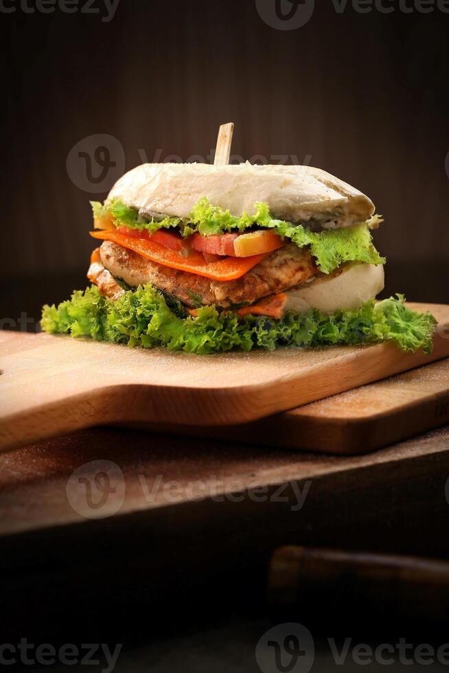 Sandwich with chicken, tomato and lettuce on a wooden board. photo