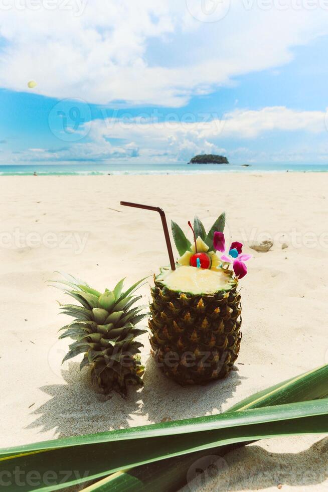 Pineapple cocktail on the beach with blue sky and sea background photo