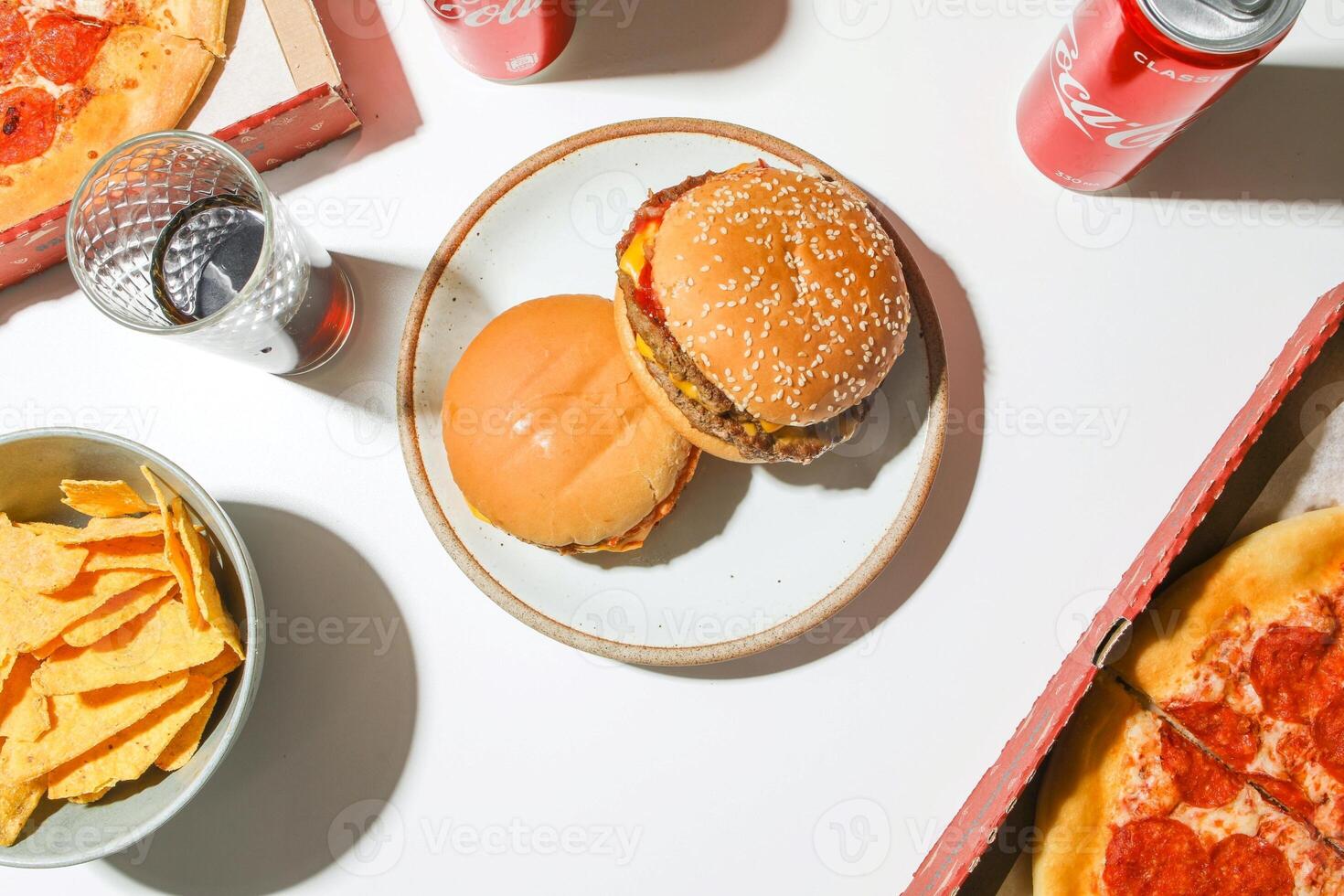 Overhead view of hamburger with chips and soda on white table photo