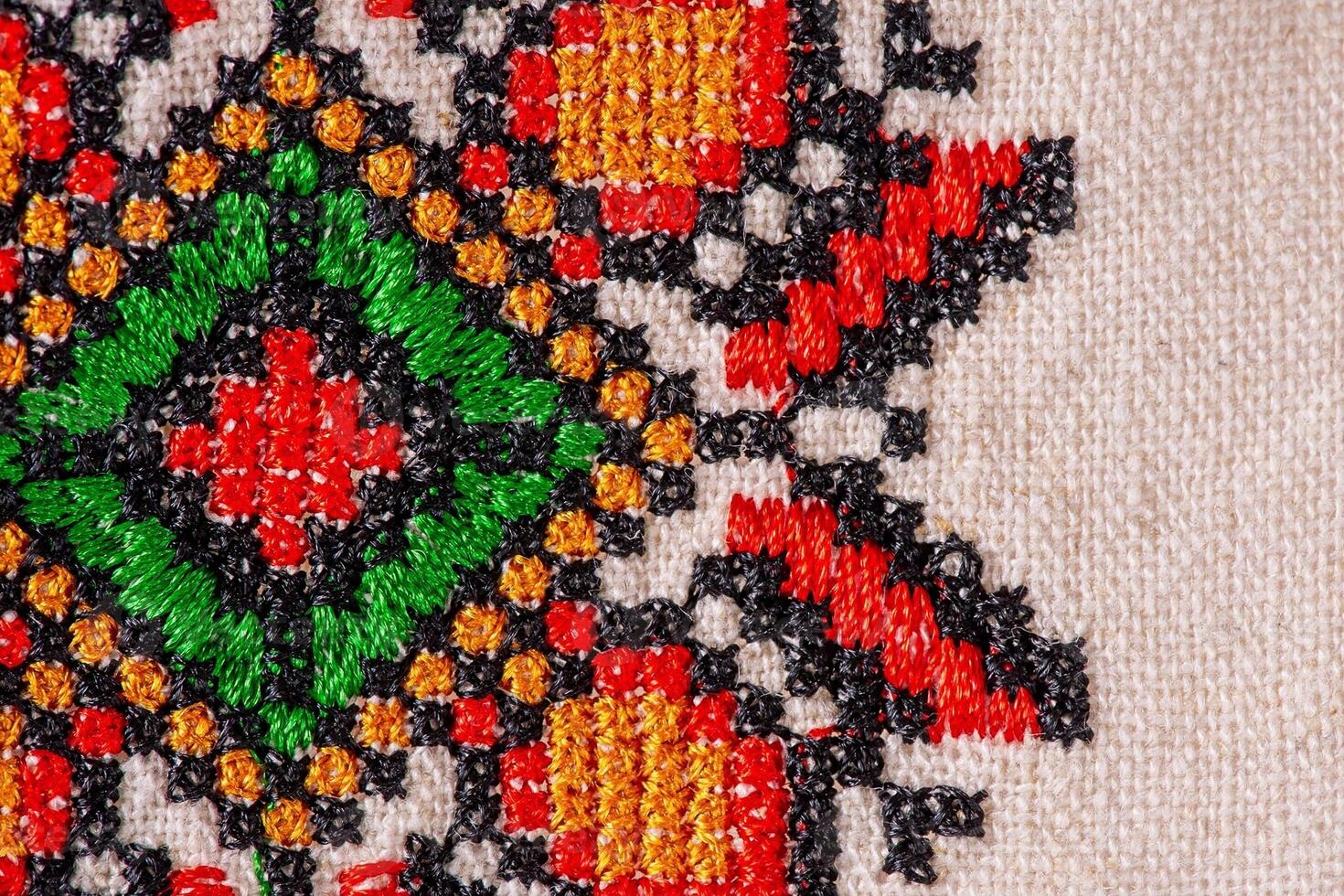 Macro photo of linen fabric with red, green, black and orange embroidery. Fabric as a background.