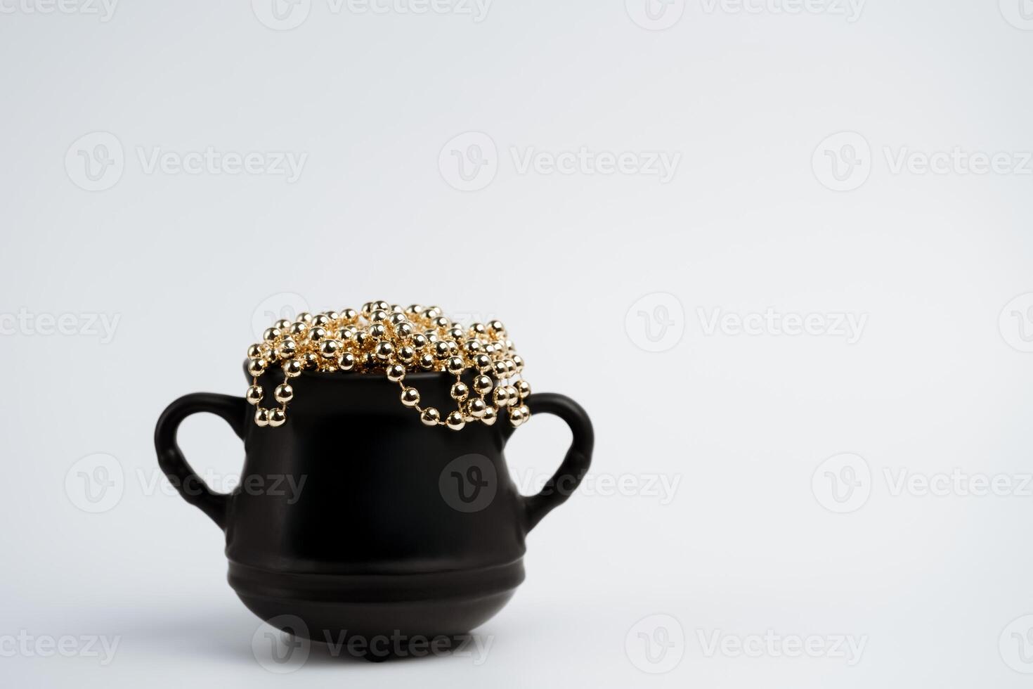 Black cauldron pot with gold beads on white background photo