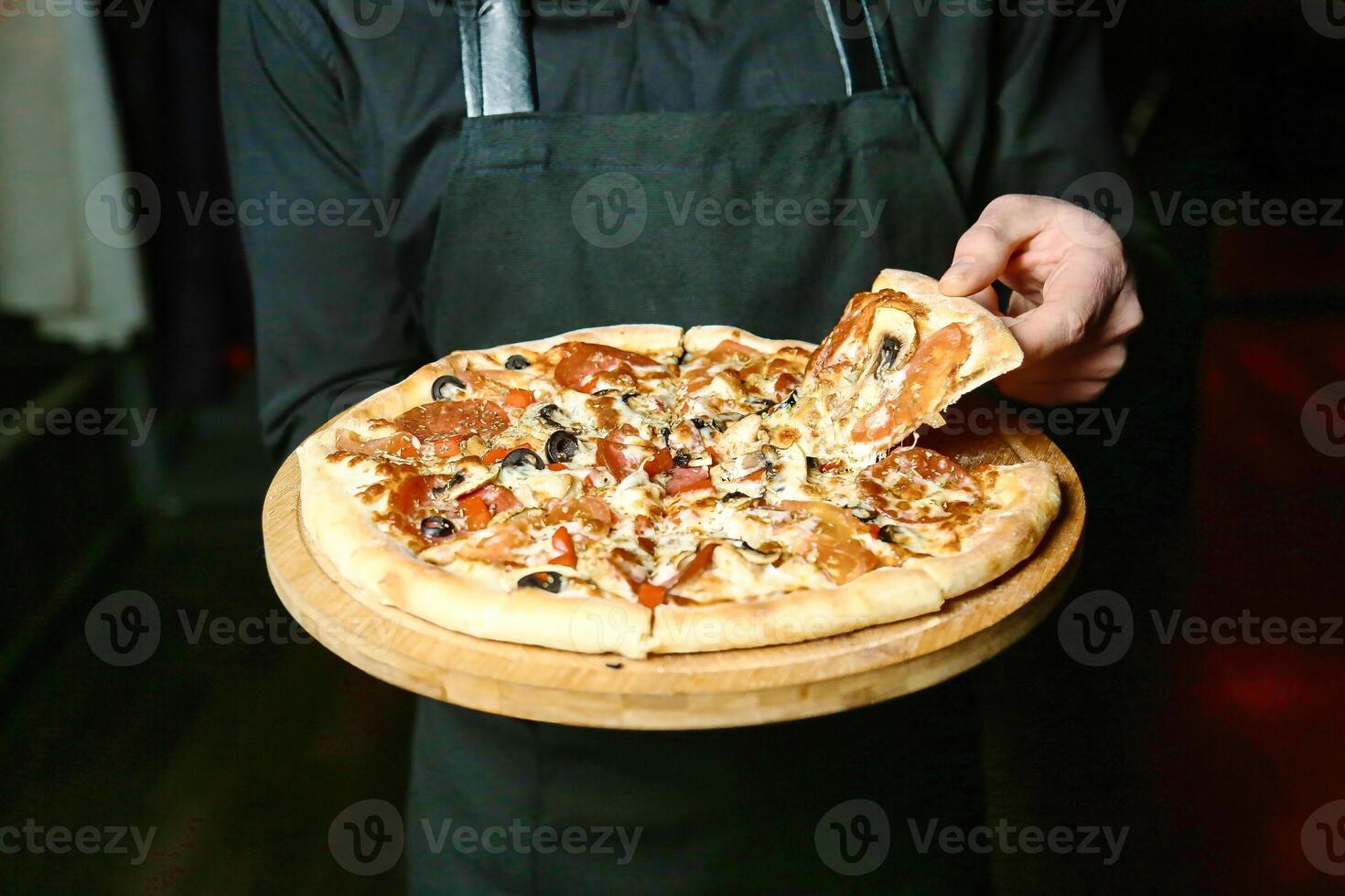 persona participación un Pizza en un de madera bandeja foto