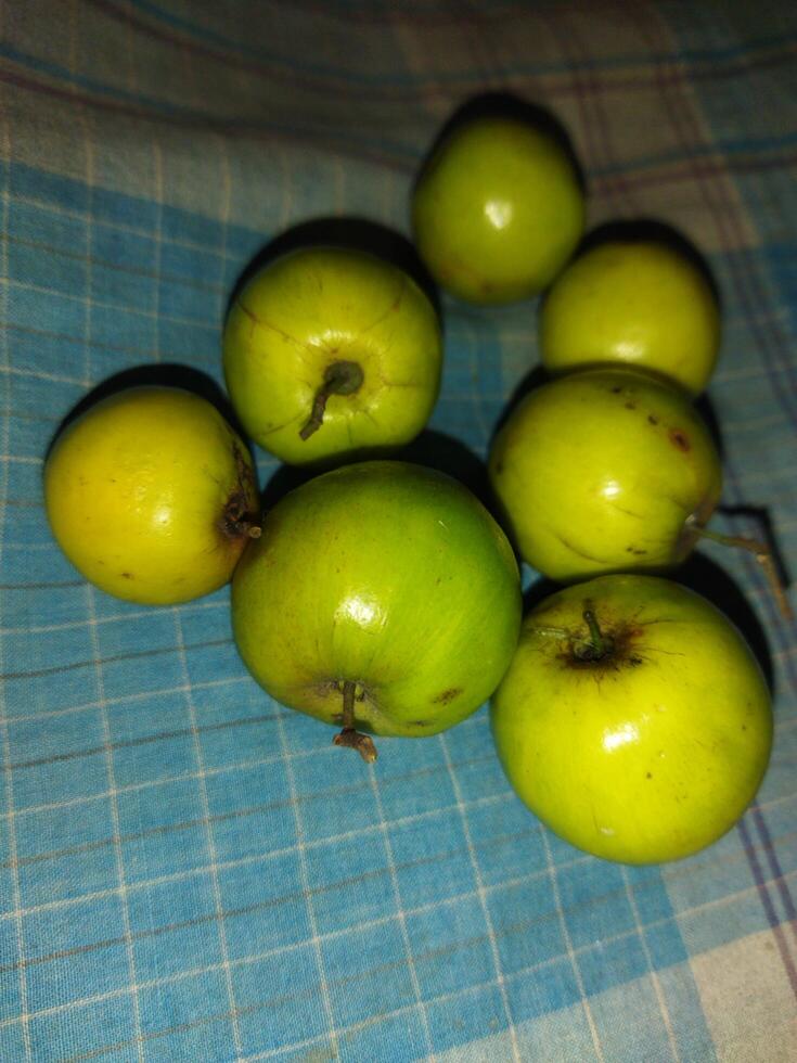 un grupo de verde manzanas sentado en un azul y blanco a cuadros mesa paño foto