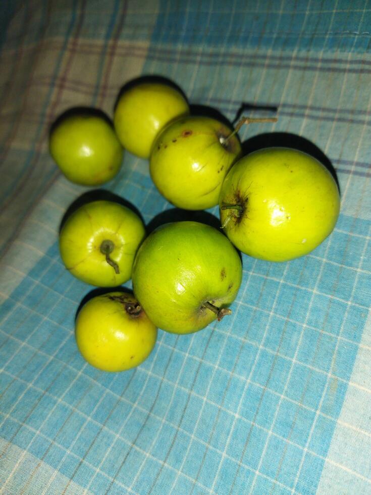 un grupo de verde manzanas sentado en un azul y blanco a cuadros mesa paño foto