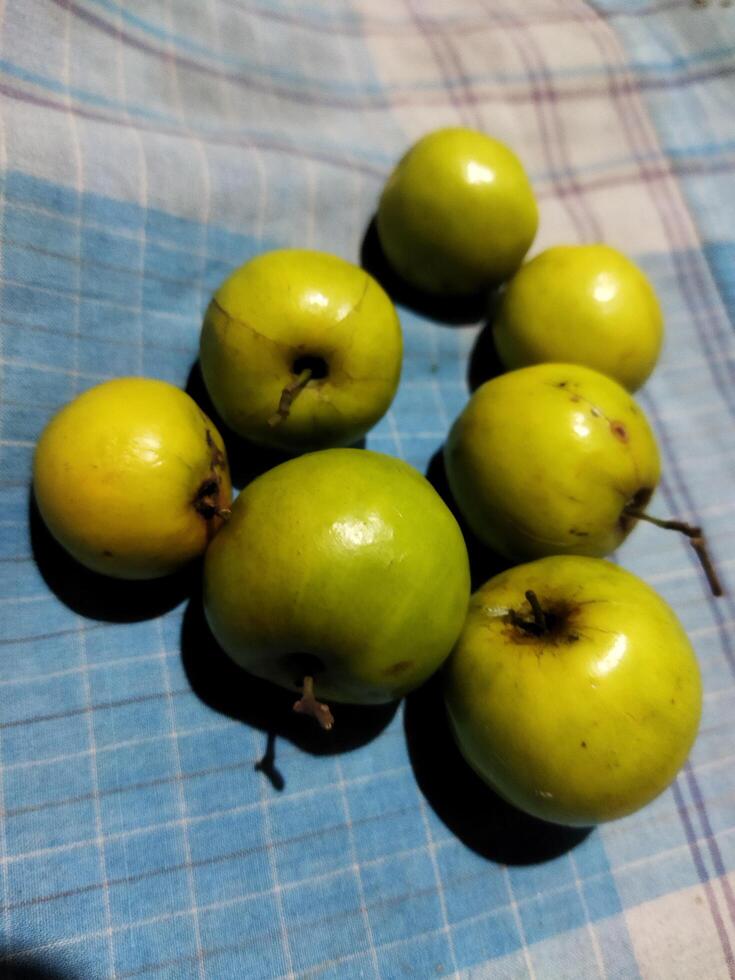 un grupo de verde manzanas sentado en un azul y blanco a cuadros mesa paño foto