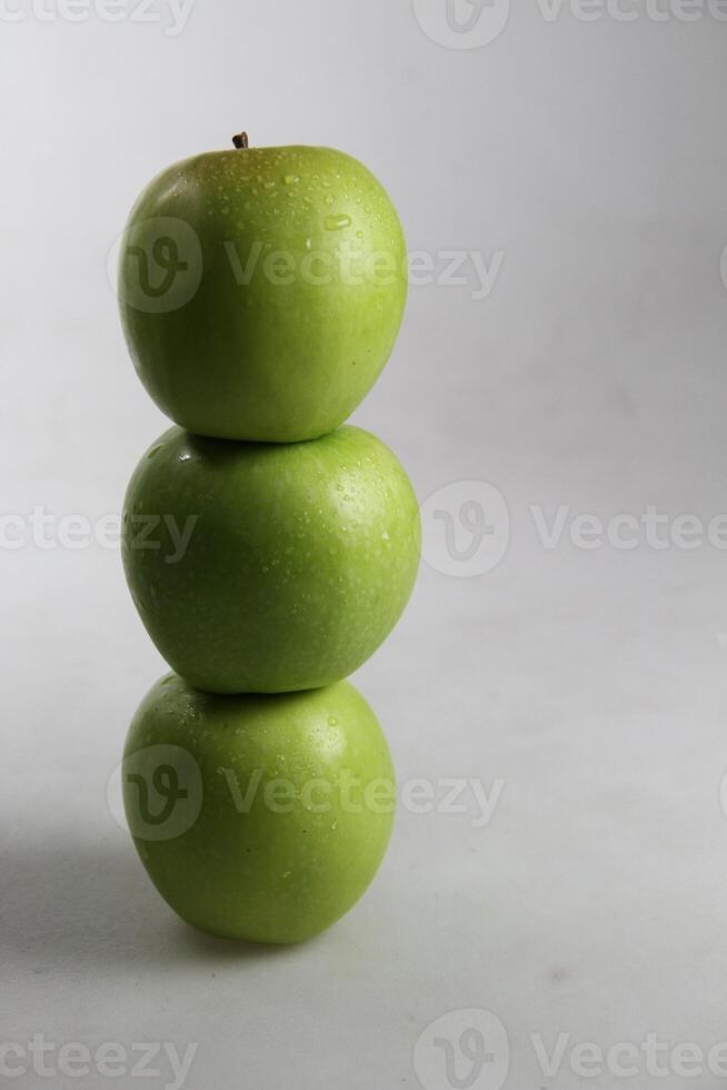 un apilar de Tres verde manzanas en blanco antecedentes foto