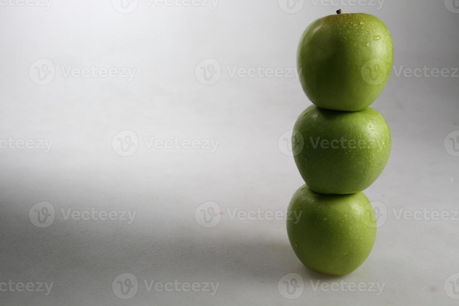 un apilar de Tres verde manzanas en blanco antecedentes foto