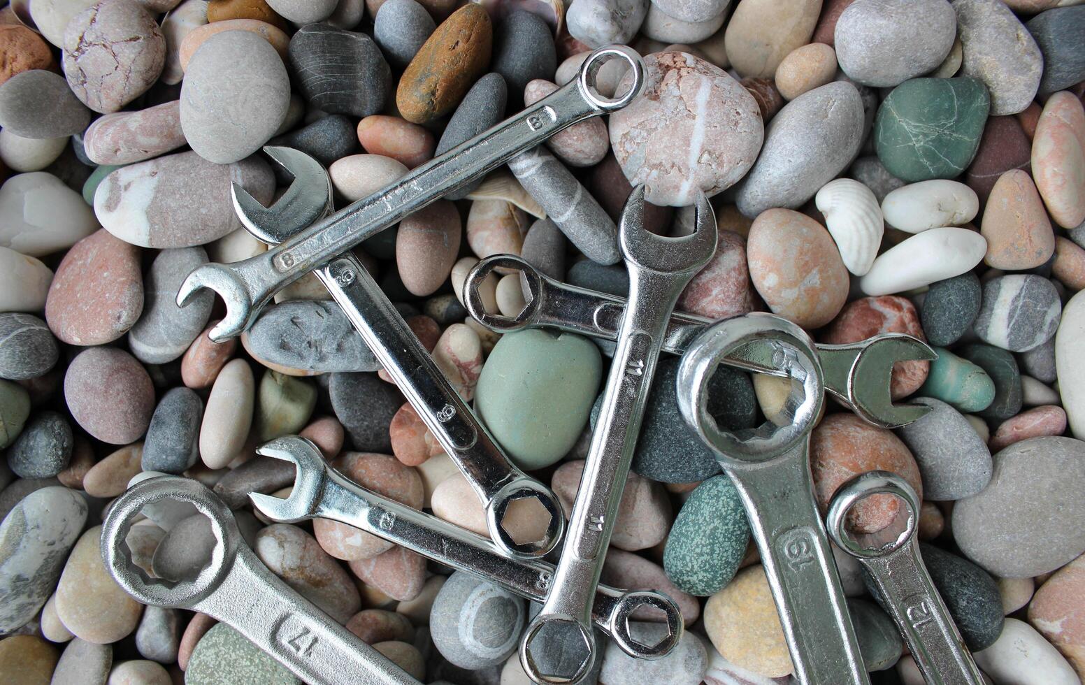 Detailed Stock Photo Of Chrome Wrenches Of Different Diameter Scattered On A Pebbles