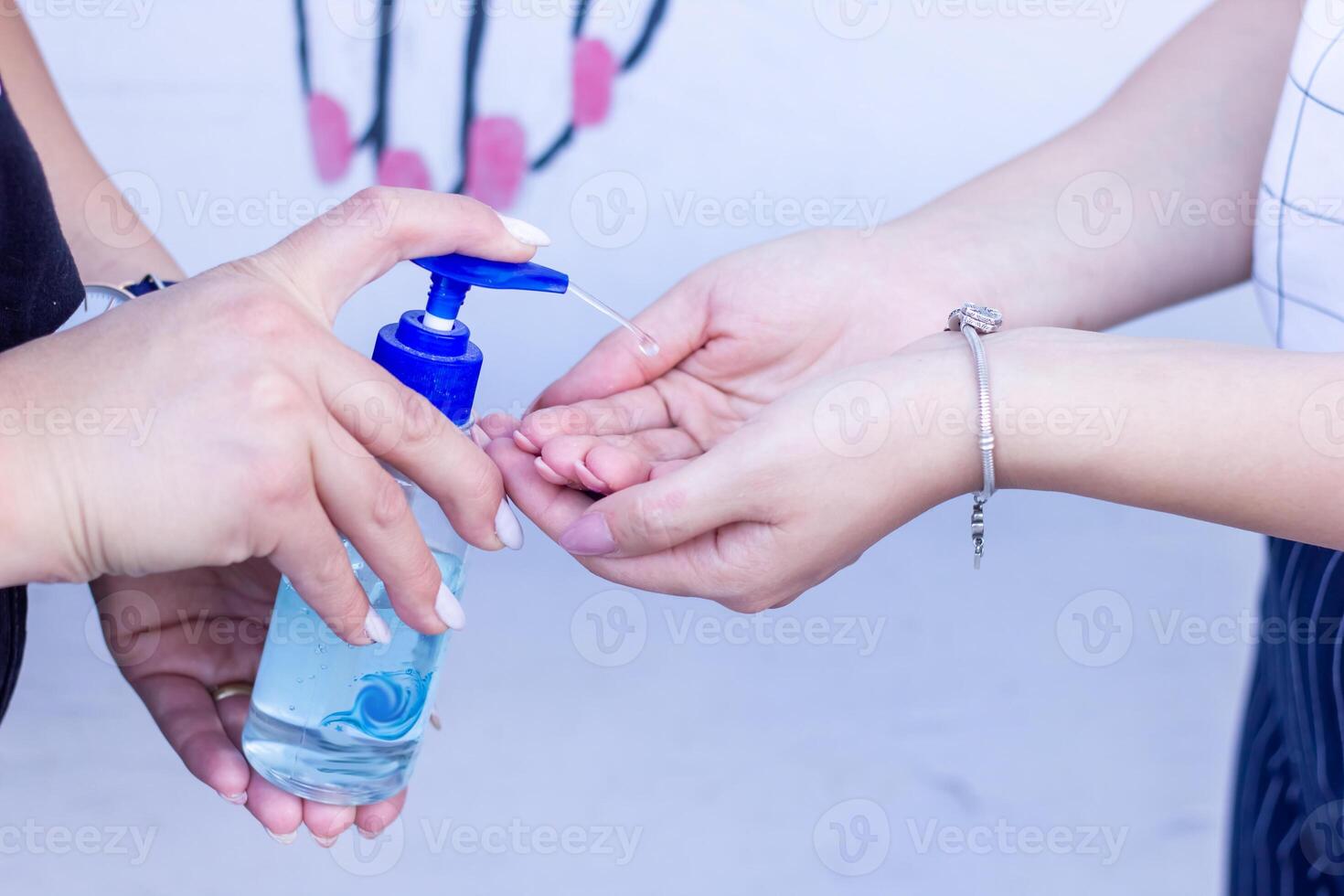 two girls washing their hands with alcogel photo