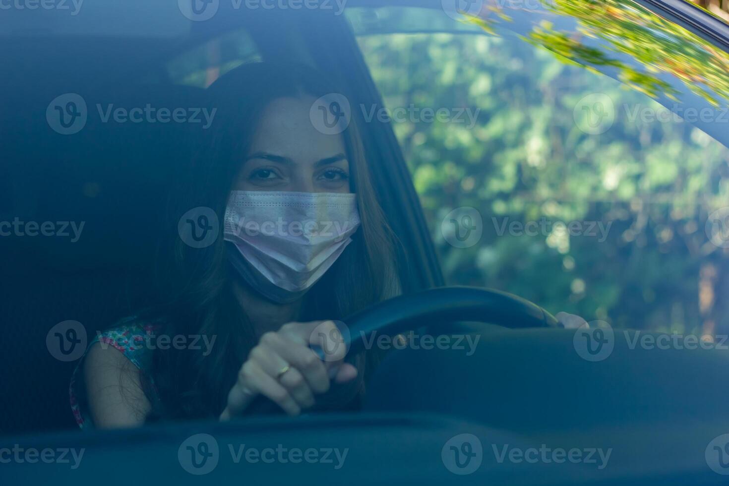 young woman in car, young woman with protective mask driving car photo