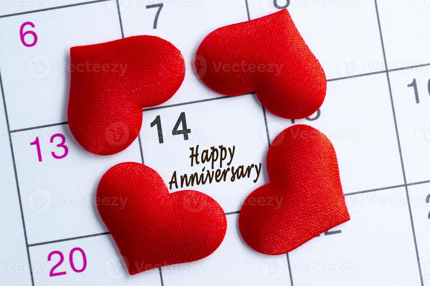 Calendar page with the red hearts on February 14 with happy anniversary text. photo